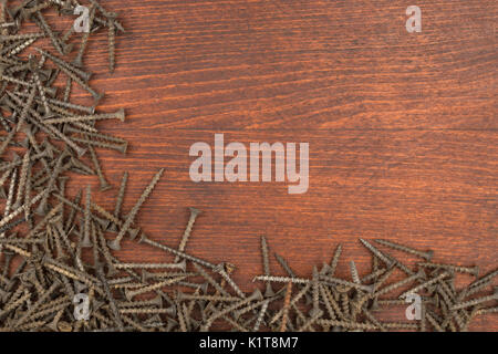 Frame of new black screws lying on a wooden surface. With space for text Stock Photo