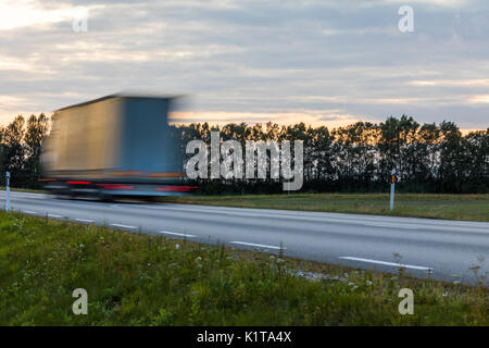 Speeding motion blur oncoming trucks with glowing lights on the highway after sunset. Abstract blur image background with copy space. Stock Photo