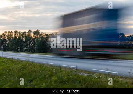 Speeding motion blur oncoming trucks with glowing lights on the highway after sunset. Abstract blur image background with copy space. Stock Photo