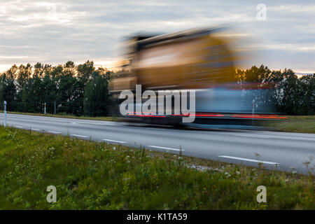 Speeding motion blur oncoming trucks with glowing lights on the highway after sunset. Abstract blur image background with copy space. Stock Photo