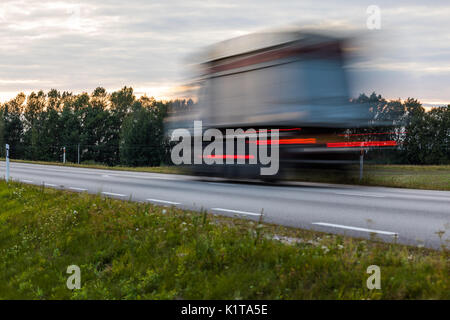 Speeding motion blur oncoming trucks with glowing lights on the highway after sunset. Abstract blur image background with copy space. Stock Photo