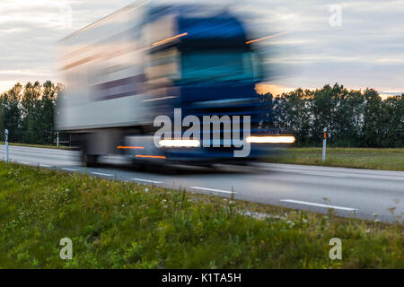 Speeding motion blur oncoming trucks with glowing lights on the highway after sunset. Abstract blur image background with copy space. Stock Photo