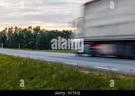 Speeding motion blur oncoming trucks with glowing lights on the highway after sunset. Abstract blur image background with copy space. Stock Photo