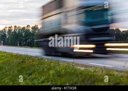 Speeding motion blur oncoming trucks with glowing lights on the highway after sunset. Abstract blur image background with copy space. Stock Photo