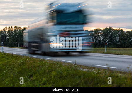 Speeding motion blur oncoming trucks with glowing lights on the highway after sunset. Abstract blur image background with copy space. Stock Photo