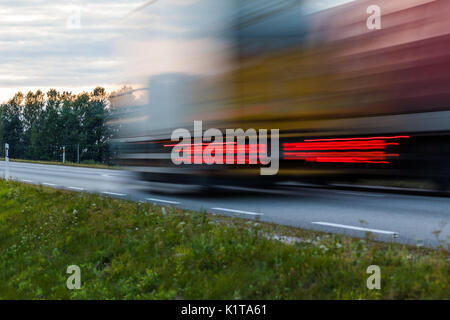 Speeding motion blur oncoming trucks with glowing lights on the highway after sunset. Abstract blur image background with copy space. Stock Photo