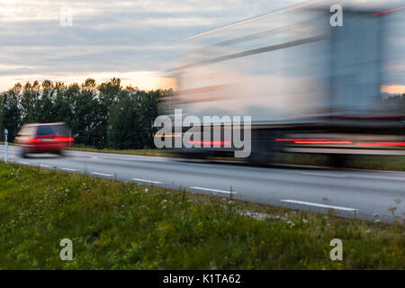 Speeding motion blur oncoming trucks with glowing lights on the highway after sunset. Abstract blur image background with copy space. Stock Photo