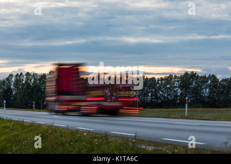 Speeding motion blur oncoming trucks with glowing lights on the highway after sunset. Abstract blur image background with copy space. Stock Photo