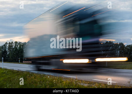 Speeding motion blur oncoming trucks with glowing lights on the highway after sunset. Abstract blur image background with copy space. Stock Photo