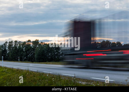 Speeding motion blur oncoming trucks with glowing lights on the highway after sunset. Abstract blur image background with copy space. Stock Photo