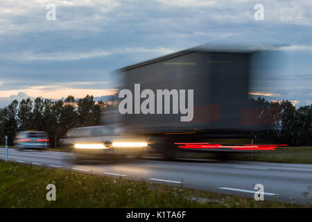 Speeding motion blur oncoming trucks with glowing lights on the highway after sunset. Abstract blur image background with copy space. Stock Photo