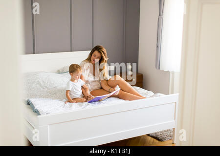 Mother and little boy reading book in bed at home Stock Photo