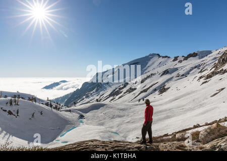 A man admires the winter view from upper Monarch Lake into the Mineral King valley of Sequoia National Park. Stock Photo