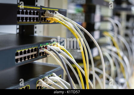 RJ45 cables plugged into switches in rack Stock Photo
