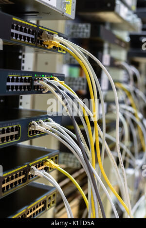 RJ45 cables plugged into switches in rack Stock Photo