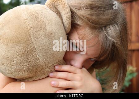 Close up portrait of little girl holding teddy bear looking intense Stock Photo