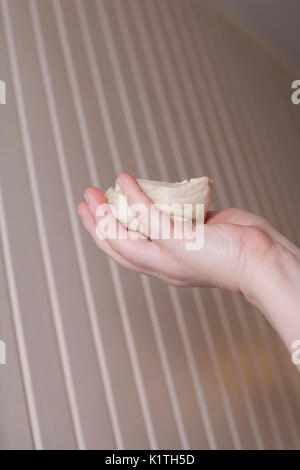 Hand holding a single raw biscuit in the air Stock Photo