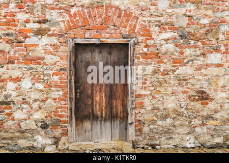 Detail view of a brick wall with an old wooden gate Stock Photo