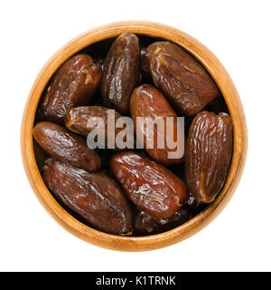 Dried Deglet Nour dates in wooden bowl. Also Deglet Noor, queen of all dates with translucent color. Algerian cultivar of Phoenix dactylifera. Stock Photo