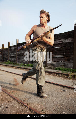 Europe, Germany, Hessen, Rhein-Main, at the pier in Frankfurt - A Soldier with a gun is running and looks after danger Stock Photo