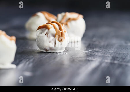 White Chocolate truffles for Christmas or Valentines's Day drizzled with peanut butter sauce. Extreme shallow depth of field with selective focus on c Stock Photo