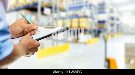 logistics service man writing documents on clipboard in warehouse Stock Photo