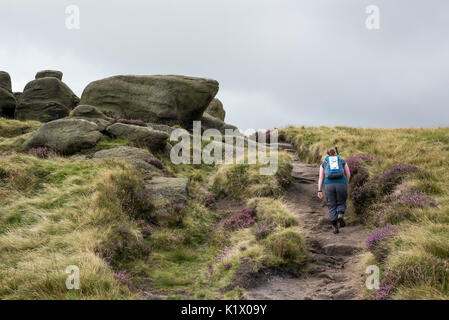 Single woman walking in rocky landscape on Kinder Scout in the Peak District, Derbyshire, England. Stock Photo