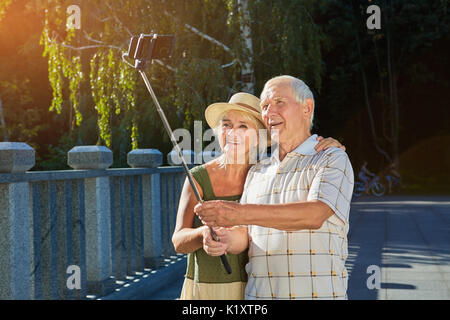 Old couple taking selfie outdoors. Senior male holding monopod. Technology  use among seniors Stock Photo - Alamy