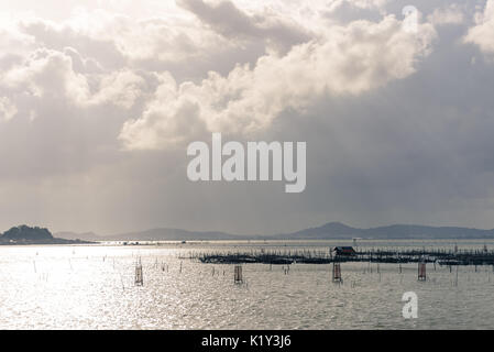 Sun shine through cloud to the hut and fish trap by local knowledge in the Songkhla Lake, Thailand. Stock Photo