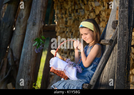 Cute smiling little girl holding a basket of flowers. Portrait in profile. Stock Photo