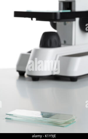 Stack of specimen holders in front of microscope over white background Stock Photo