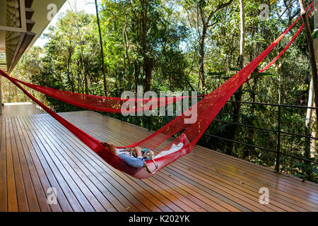 People resting on red hammocks hanging on the Tunga Gallery, Inhotim Cultural Institute, Brumadinho, Belo Horizonte, Minas Gerais, Brazil. Stock Photo