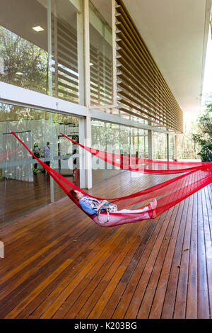 People resting on red hammocks hanging on the Tunga Gallery, Inhotim Cultural Institute, Brumadinho, Belo Horizonte, Minas Gerais, Brazil. Stock Photo