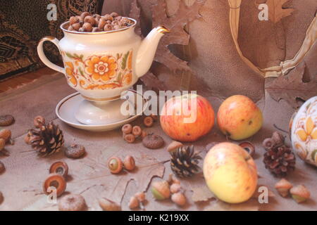 retro style tea set full oak acorns decorated with dry brown leaves and flowers, fir cones and juicy pink apples Stock Photo