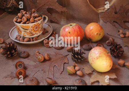 retro style tea set full oak acorns decorated with dry brown leaves and flowers, fir cones and juicy pink apples Stock Photo