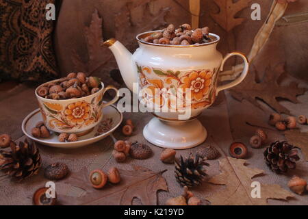 retro style tea set full oak acorns decorated with dry brown leaves and flowers, fir cones and juicy pink apples Stock Photo