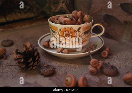 retro style tea set full oak acorns decorated with dry brown leaves and flowers, fir cones and juicy pink apples Stock Photo