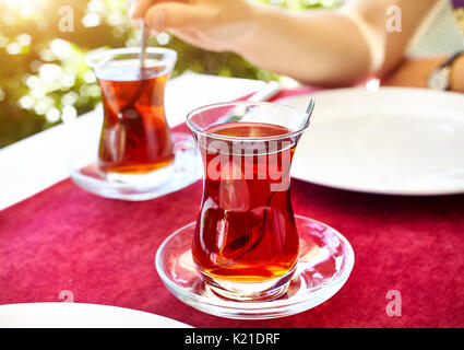 Turkish tea in traditional glass in restaurant on the red table in Turkey Stock Photo