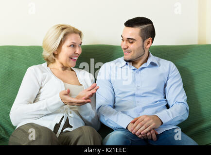 Smiling young man and senior woman having pleasant conversation indoor Stock Photo