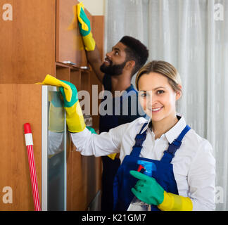 Smiling Professional Female Cleaners Washing Apartment With Rags