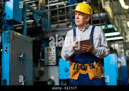 Senior Factory Worker Using Tablet Stock Photo