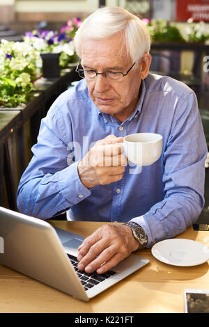 Modern Senior Man Using Laptop  at Coffee Break Stock Photo