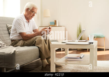 Senior Man Using Smartphone at Home Stock Photo