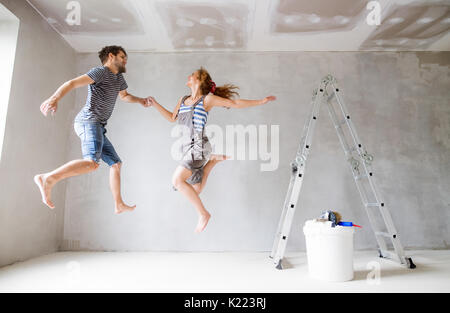 Young couple painting walls in their new house. Stock Photo