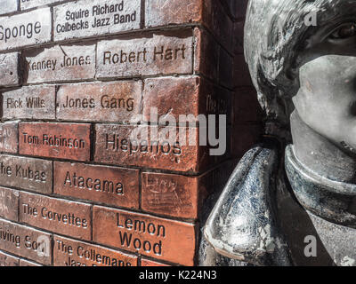 Close up of John Lennon of the Beatles statue with The Cavern Wall of Fame, Mathew Street, Liverpool, England, UK Stock Photo