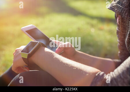 Female athlete using fitness app on her smart watch to monitor workout performance. Lifestyle wearable technology concept with lens flare. Stock Photo