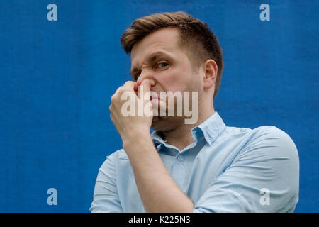 portrait of young caucasian man closing his nose because of terrible smelling Stock Photo
