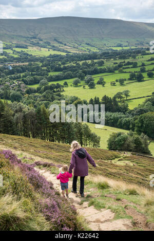 Mature woman helping a young girl down a steep hillside above Edale in the Peak District national park, Derbyshire, England. Stock Photo