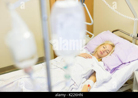 Bedridden female patient recovering after surgery in hospital care. Stock Photo