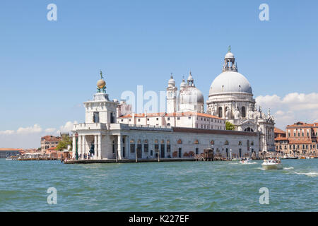 View from the lagoon of Punta della Dogana and Basilica Santa Maria della Salute, Venice, Italy on a sunny day with tourists and water taxis. This use Stock Photo